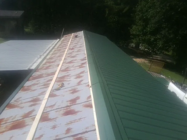 Old rusted panels beside newly installed green metal roofing — Wind Damage Roof Repair by Roofing Brothers in Labadie