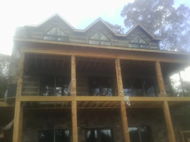 Dormers and porch framing on a large log home under construction — Roof Coating work by our crew in Labadie