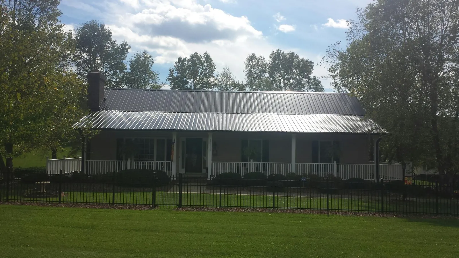 Gray metal roof on a brick ranch with a full width front porch — Gutter Guard Installation work by our crew in Labadie